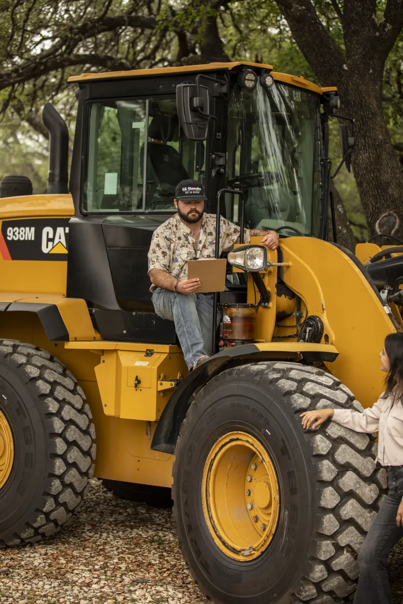 Operator with a clipboard climbing a loader cab step