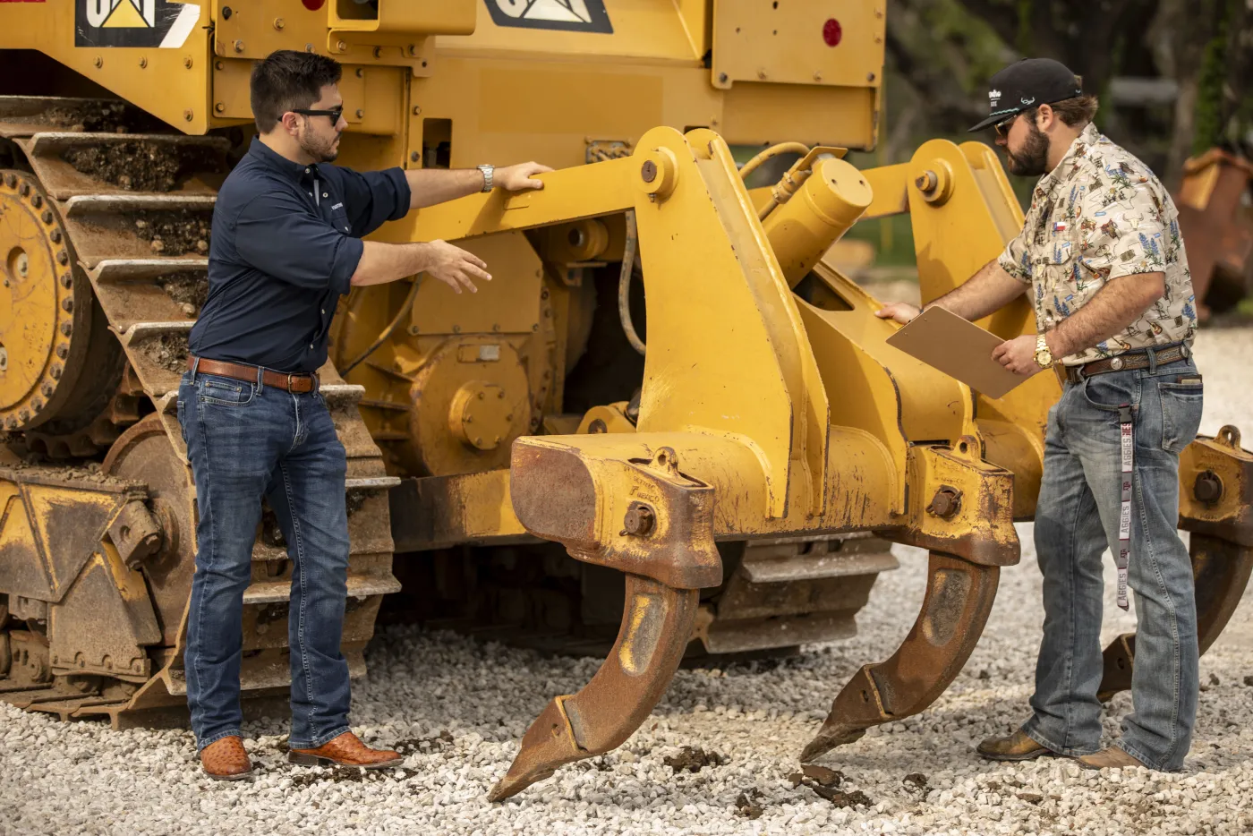 Two team members walking around a CAT dozer ripper assembly